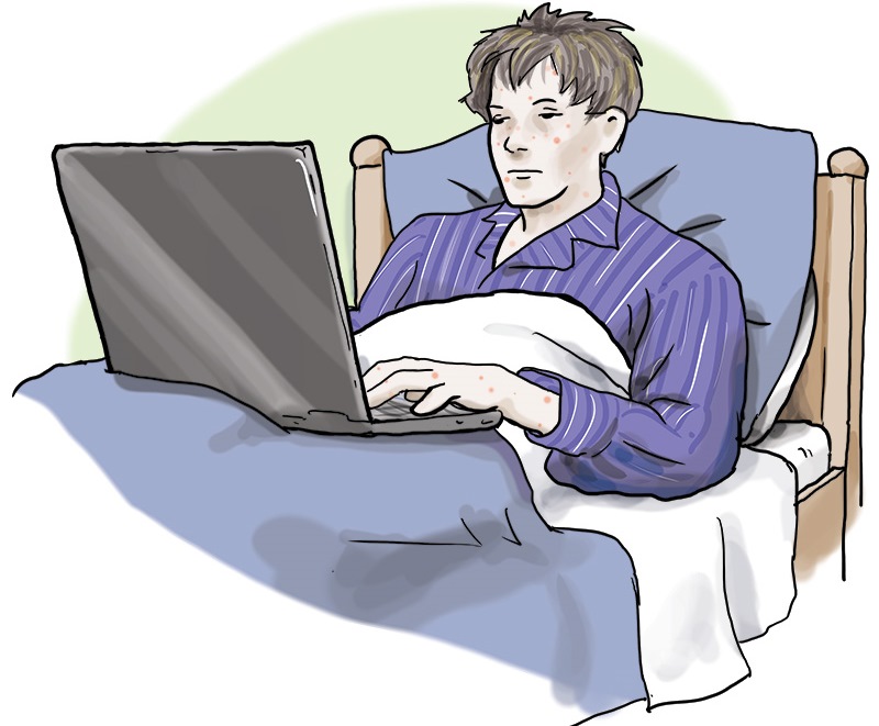 Eine kranke Person im Bett, mit einem Laptop auf dem Schoß
