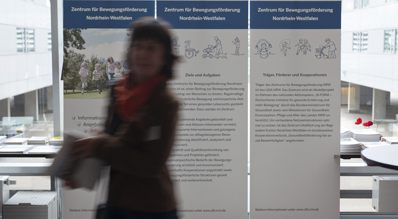 Teilnehmerin mit Informationsmaterial auf der Ausstellungsfläche